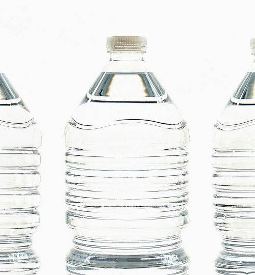 Three clear plastic bottles filled with water, standing side by side.